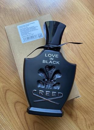 Creed Love In Black bottle photographed on wooden surface with tester sticker on cap